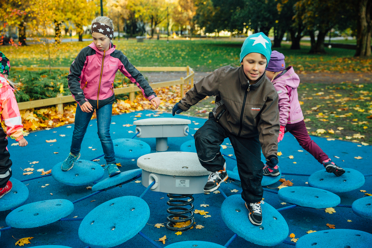 balancing playground equipment in small park with safety surfacing