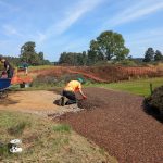Redlynch Leisure team installing TigerTrak surface using wheelbarrows and hand tools