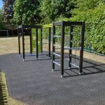 Rear view of Lappset climbing frame on grass mats, installed in an open school play area with green surroundings.