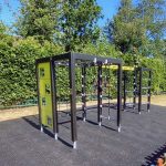 Close-up of Lappset playground equipment with climbing features and grass mats installed as safety surfacing.