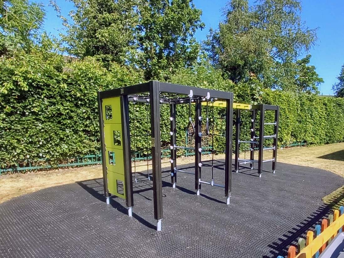 Close-up of Lappset playground equipment with climbing features and grass mats installed as safety surfacing.